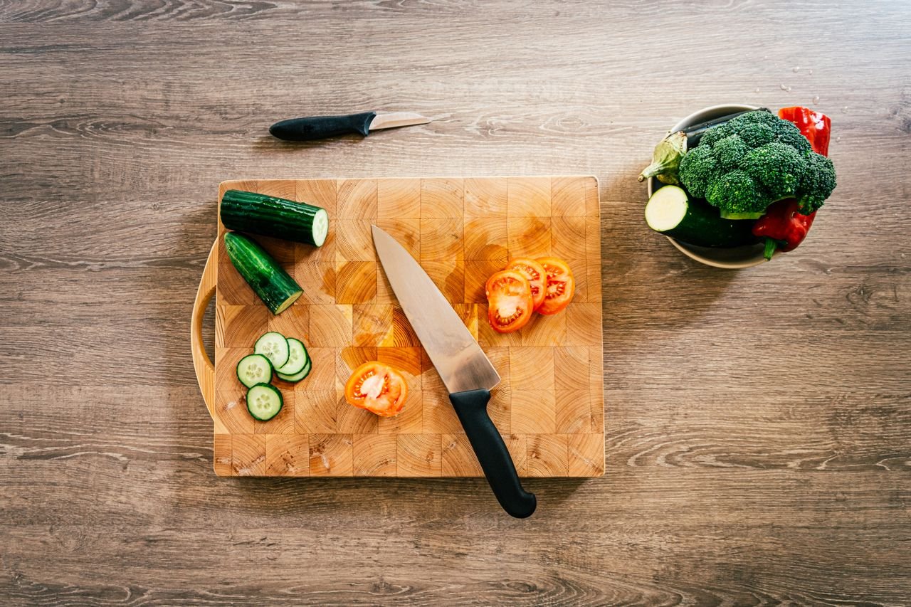 Tabla de cortar y cuchillo de chef sobre una encimera de cocina.